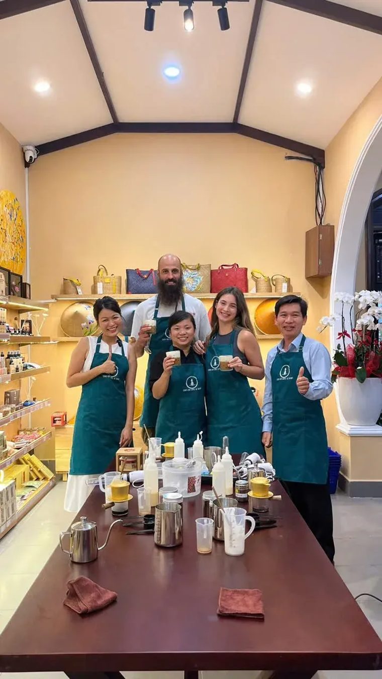 Học viên và nhân viên trong tạp dề xanh chụp ảnh chung sau buổi học pha cà phê tại Cam On Cafe.