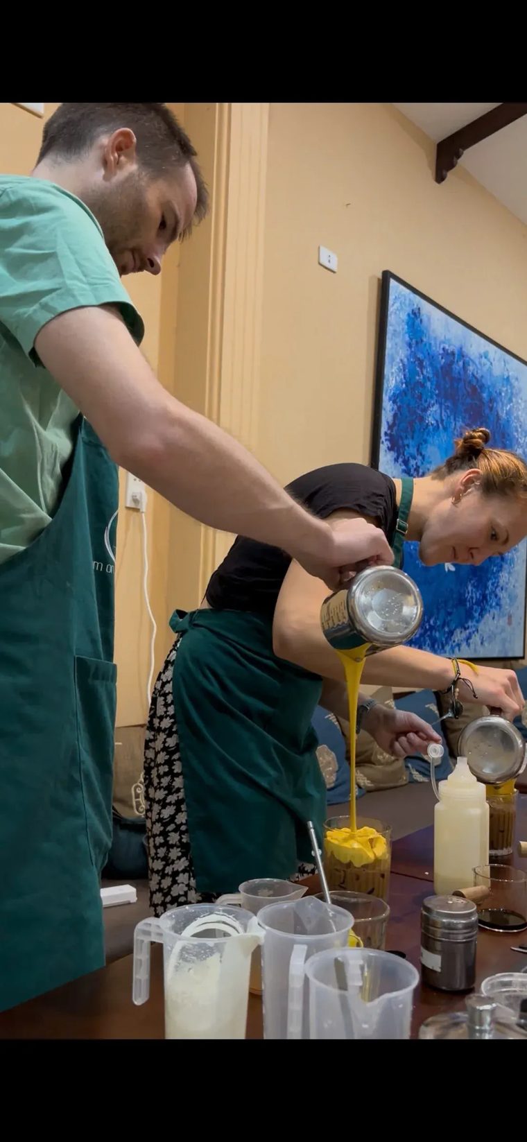 Một vị khách rót lớp kem trứng vàng vào ly cà phê đá trong lớp học tại Cam On Cafe.