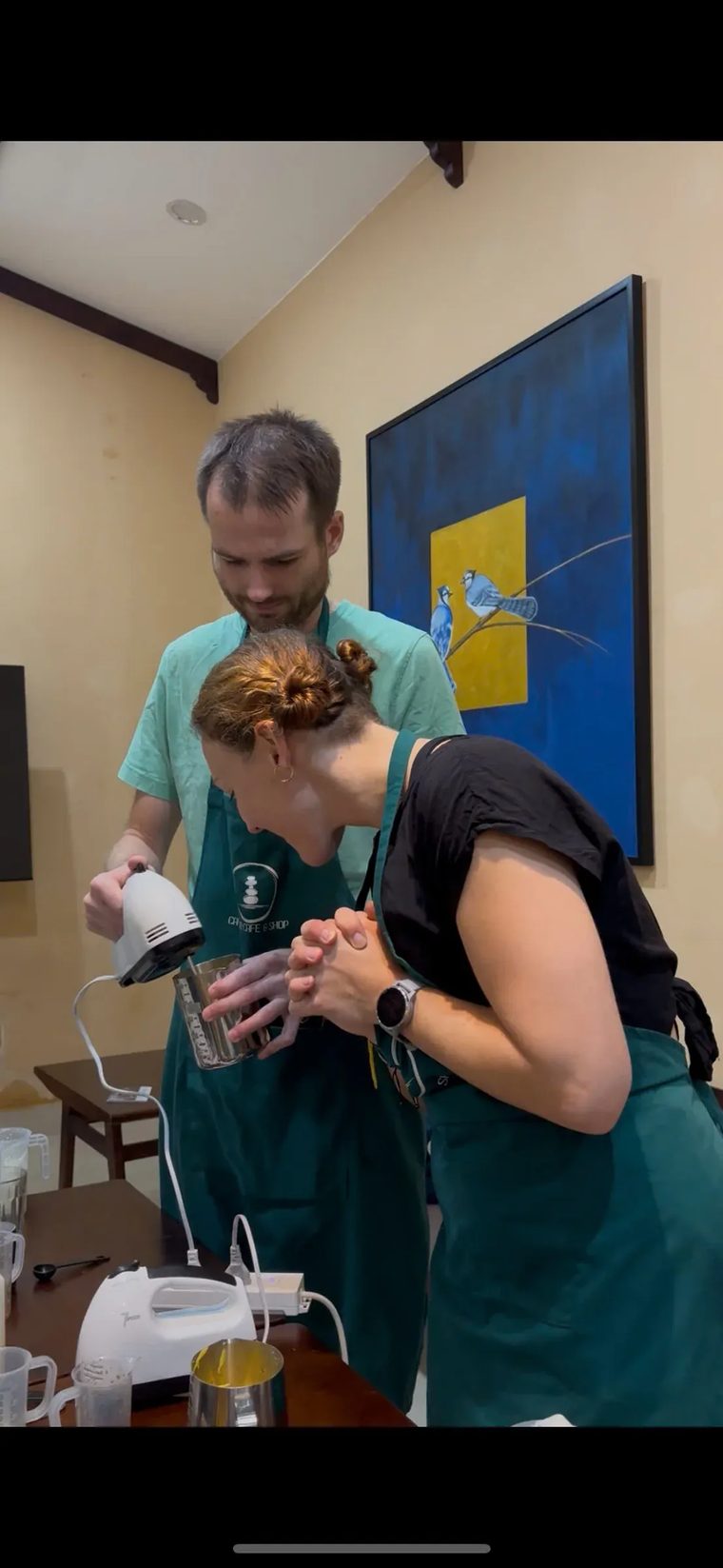 Hai du khách nước ngoài dùng máy đánh cầm tay làm lớp kem cà phê tại Cam On Cafe.
