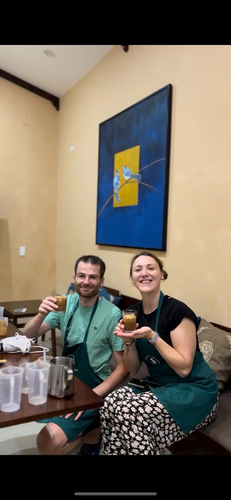 Hai du khách tươi cười trong tạp dề khoe ly cà phê Việt tự tay pha trong buổi học tại Cam On Cafe.