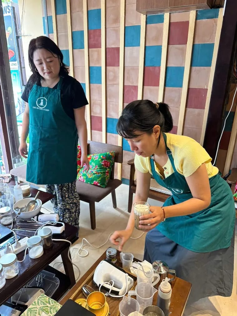 Một vị khách nữ cầm ly cà phê muối trong buổi học pha chế tại Cam On Cafe.
