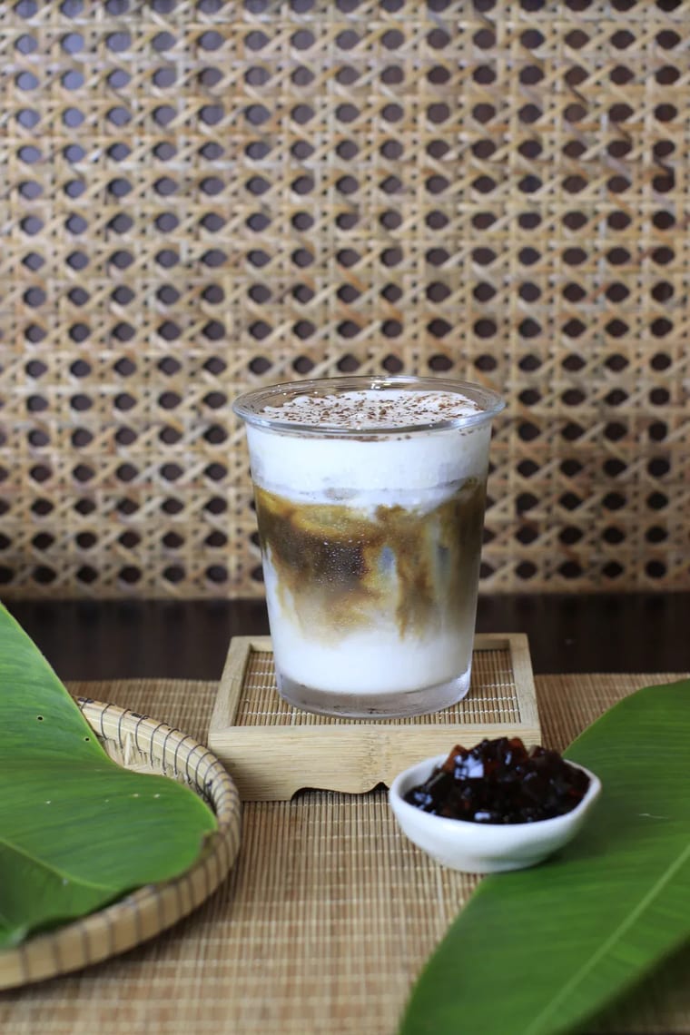 Ly cà phê hạnh nhân đá kiểu Việt đặt trên đế lót gỗ tại Cam On Cafe.