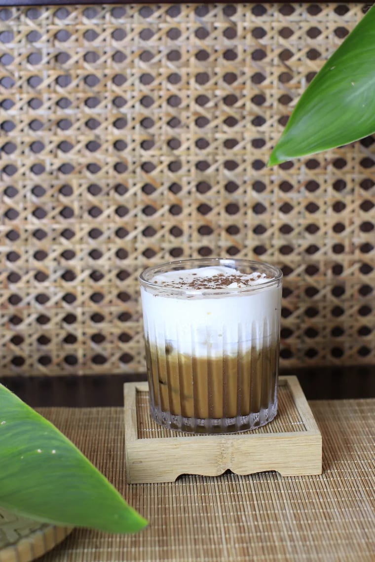 Ly cà phê đá với lớp bọt kem dày, phục vụ trên khay gỗ tại Cam On Cafe.