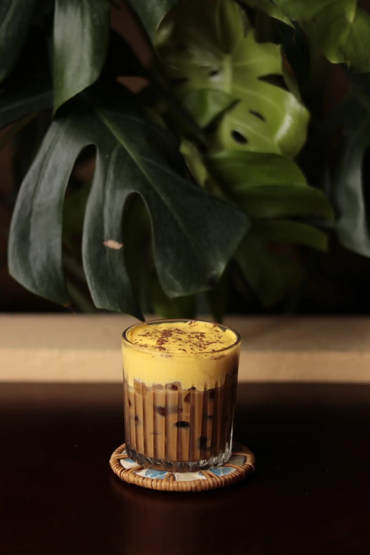 Ly cà phê trứng đá phủ lớp bọt vàng, đặt trên bàn tại Cam On Cafe.