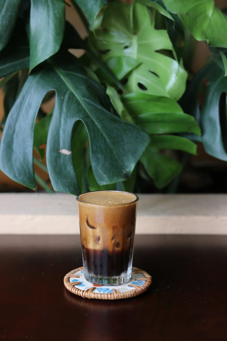 Ly cà phê đá Việt Nam với lớp bọt đầy đặn, phục vụ trên đế lót tại Cam On Cafe.