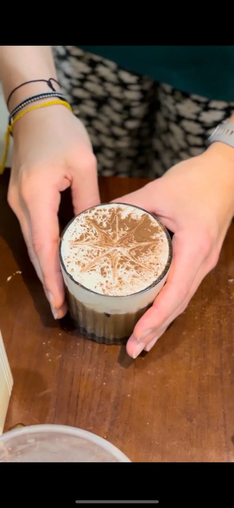 Đôi bàn tay cầm ly cà phê Việt phủ lớp bọt kem dày tại Cam On Cafe.