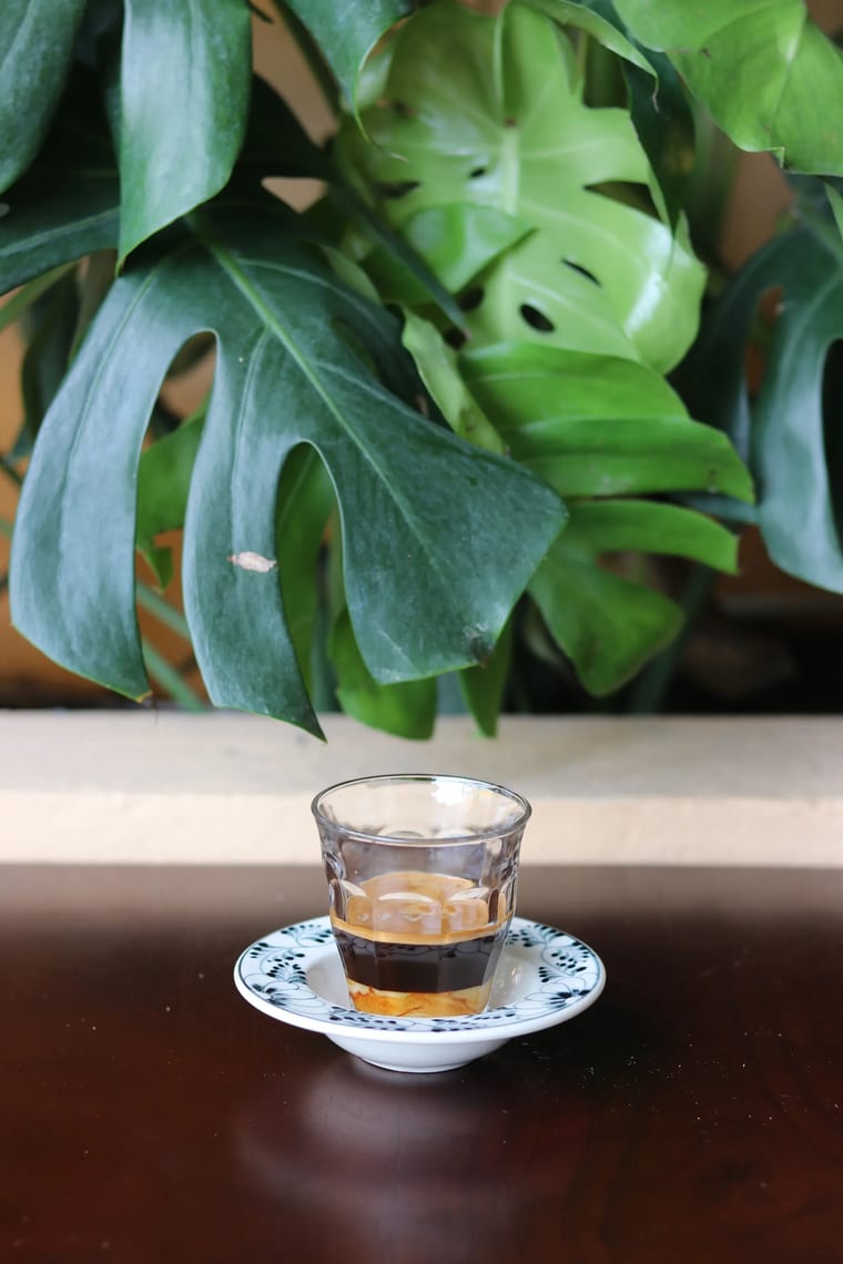 Ly nhỏ đựng cà phê đậm đặc kiểu Việt pha sữa đặc, đặt trên bàn gỗ tại Cam On Cafe.