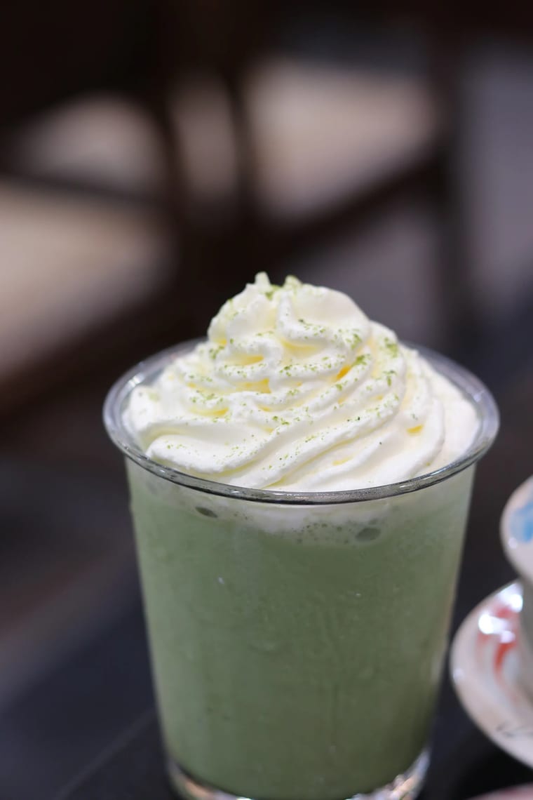 Ly thuỷ tinh đựng matcha đá phủ kem tươi bên trong Cam On Cafe.
