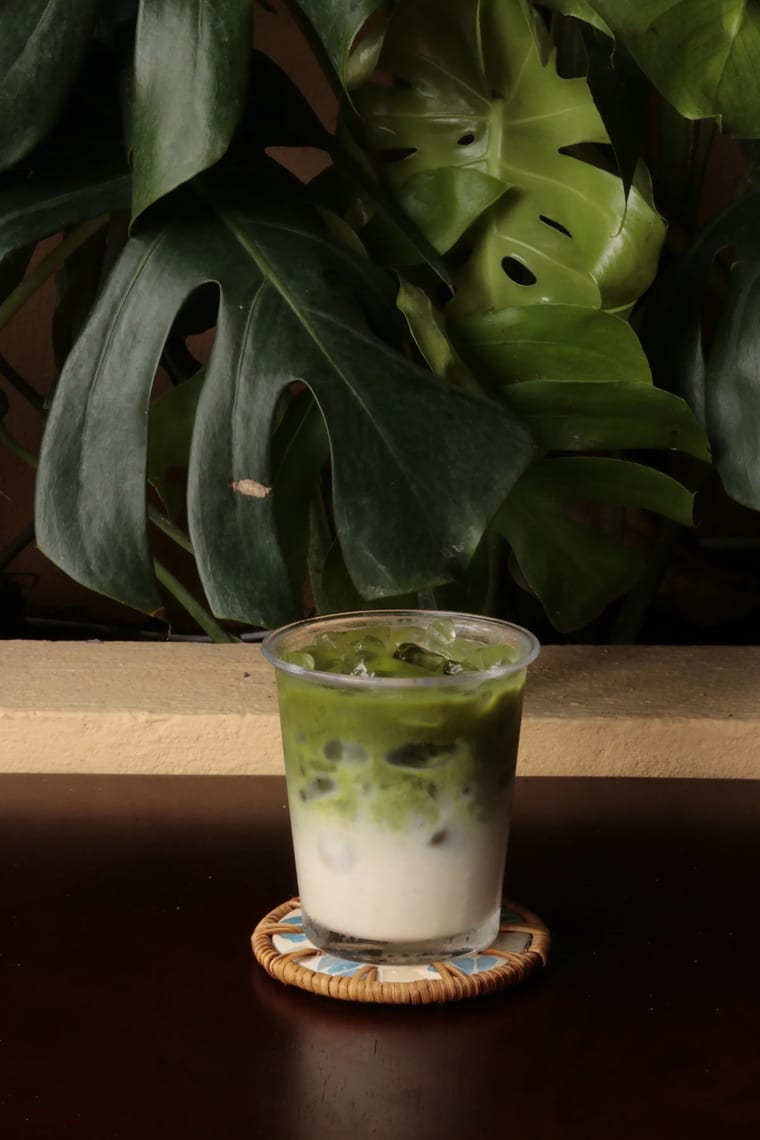 Ly matcha latte đá phục vụ trên đế lót đan tại Cam On Cafe.