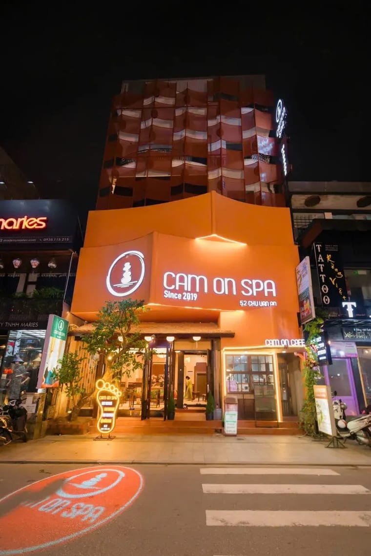 Mặt tiền màu cam rực sáng của Cam On Cafe and Spa về đêm tại Huế, Việt Nam.
