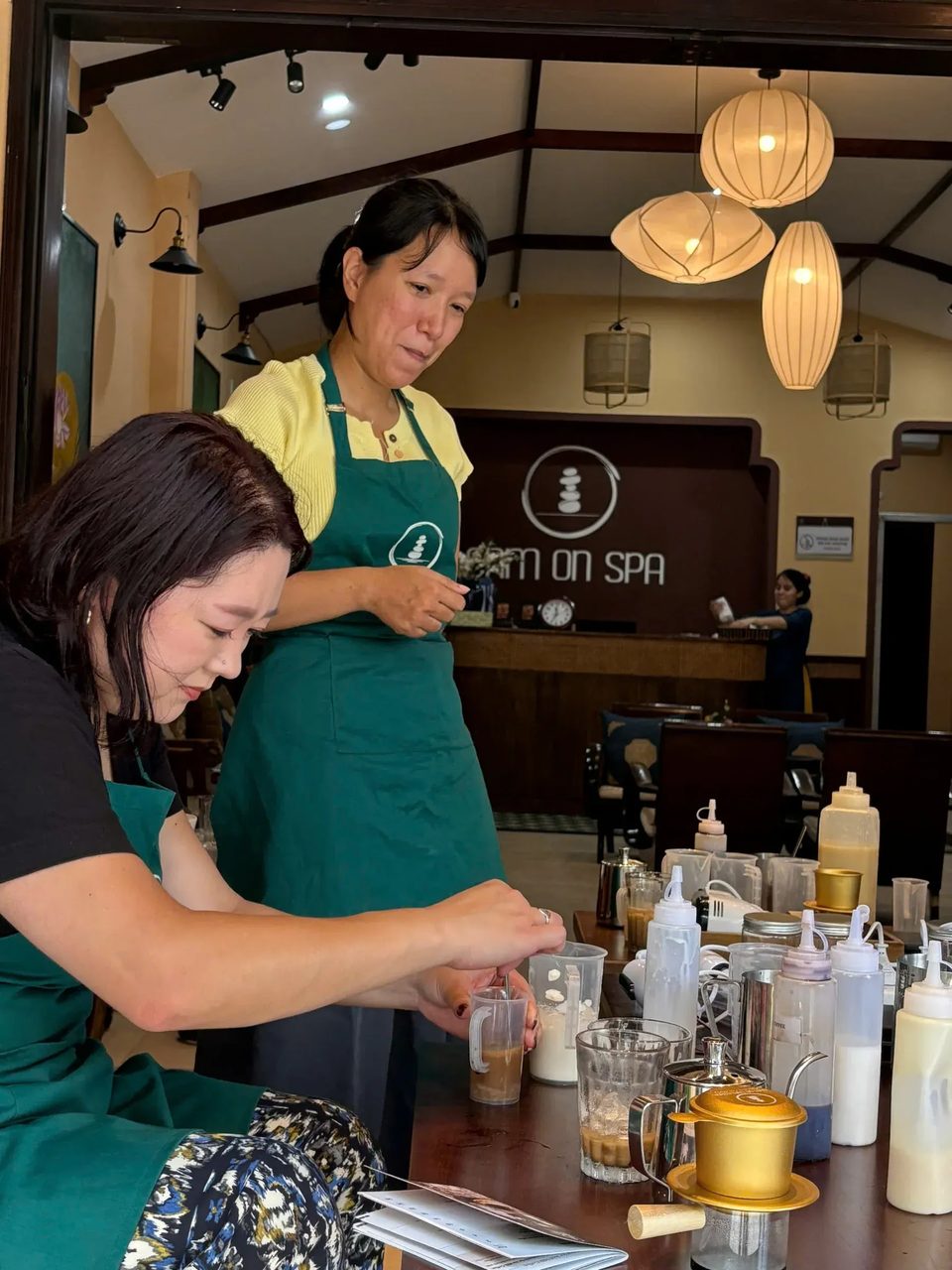 Một vị khách khuấy cà phê trong cốc đong dưới sự hướng dẫn tại Cam On Cafe.